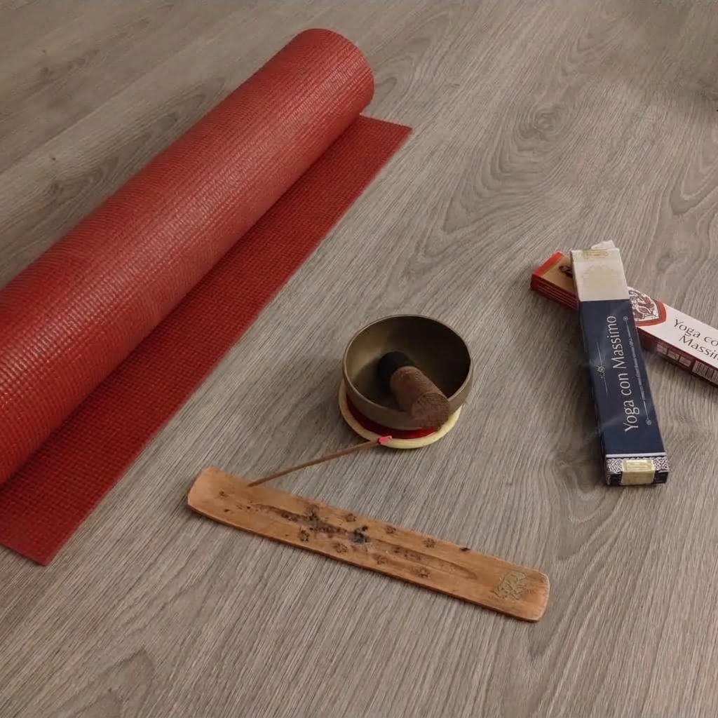 Una composizione minimalista ed elegante con un tappetino da yoga arrotolato, una campana tibetana tradizionale in bronzo, bastoncini di incenso Yoga con Massimo e un portaincenso in legno, ideale per l'atmosfera di un workshop tematico di yoga.